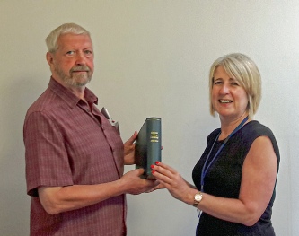 Peter Griffiths presenting the old Barling School Log Book to acting Head Teacher, Sue Clarke.
