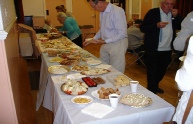 Roger Myles-Hook standing beside the food table with Derek Beadell to his right